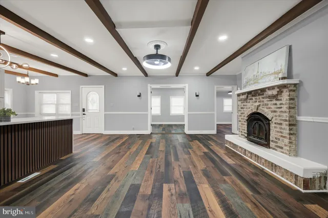 a view of an empty room with wooden floor fireplace and a window