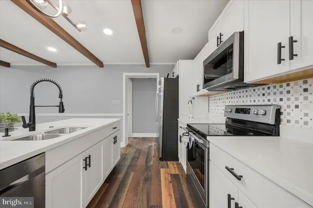 a kitchen with stainless steel appliances granite countertop a white stove top oven a sink dishwasher and a refrigerator with wooden floor