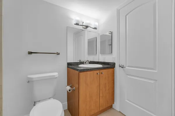 a bathroom with a granite countertop sink a toilet a mirror and shower