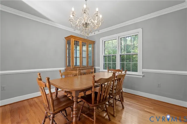a view of a dining room with furniture a chandelier and wooden floor