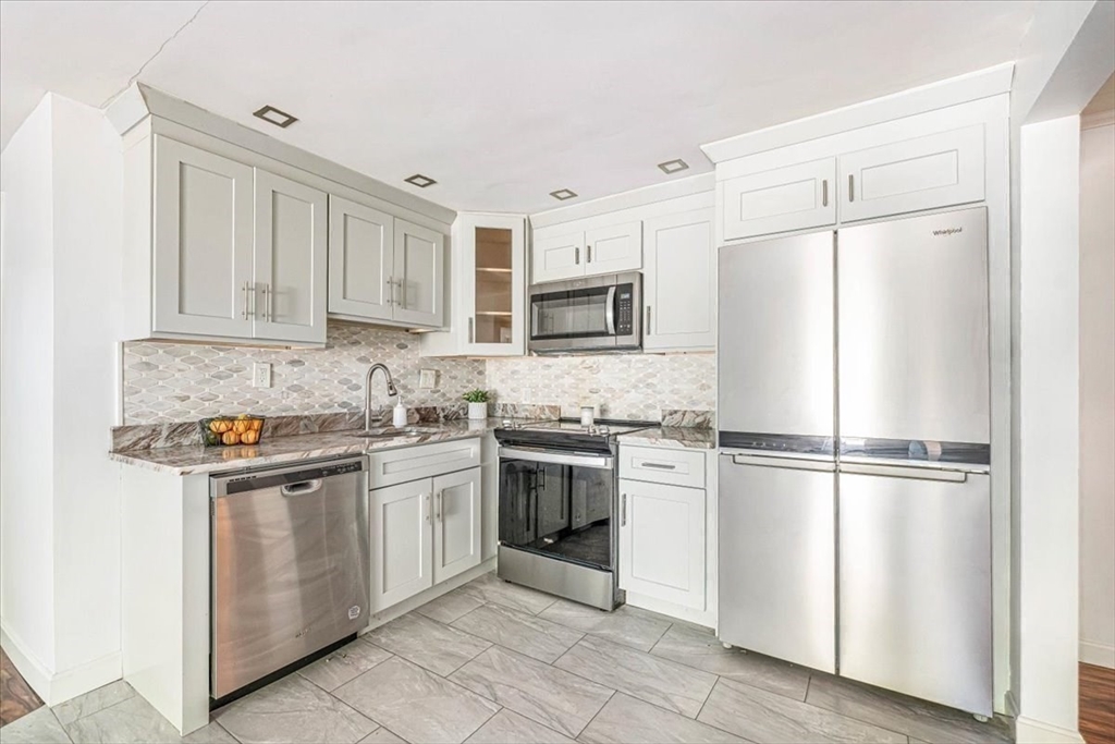 90-92 Sandwich Road, Unit 2D Bourne, MA 02532 - Photo 11 of 29 a kitchen with stainless steel appliances granite countertop a refrigerator a stove a sink and white cabinets