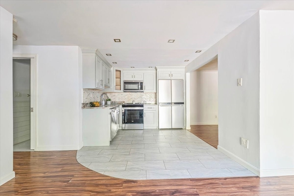 90-92 Sandwich Road, Unit 2D Bourne, MA 02532 - Photo 22 of 29 a kitchen with white cabinets and stainless steel appliances