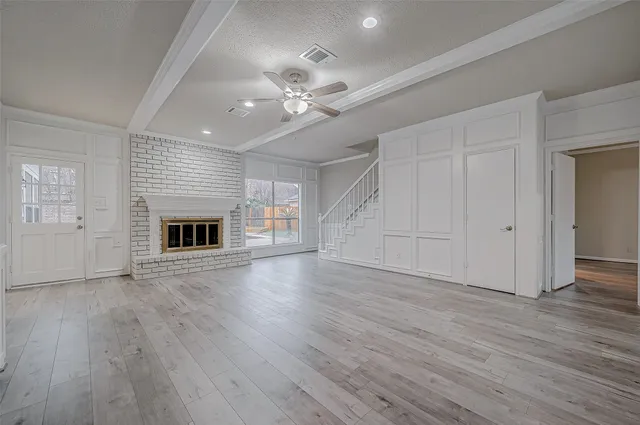 an empty room with wooden floor fireplace and ceiling fan