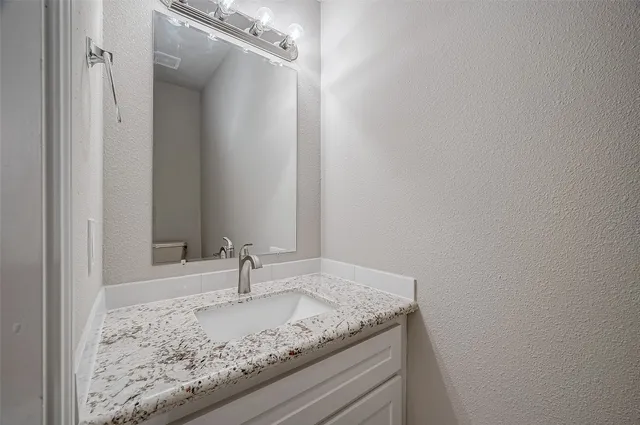 a bathroom with a granite countertop sink and vanity