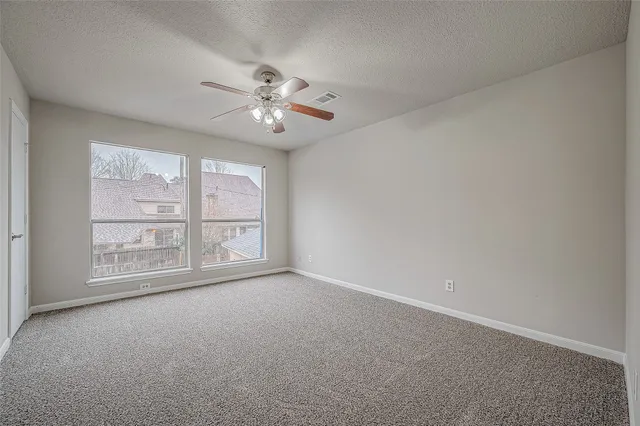 an empty room with chandelier fan and windows