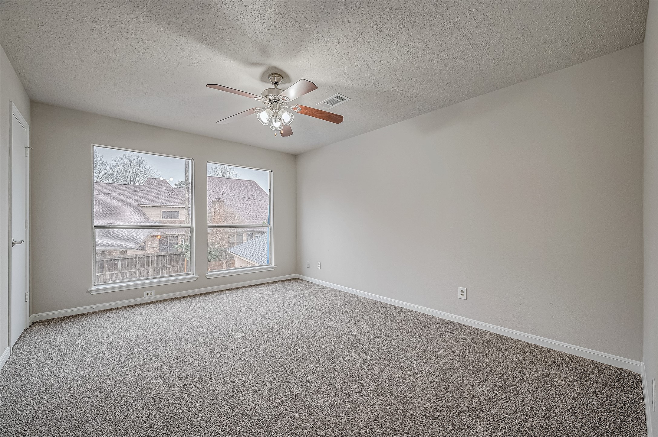 4218 Bayglen Court Houston, TX 77068 - Photo 25 of 42 an empty room with chandelier fan and windows