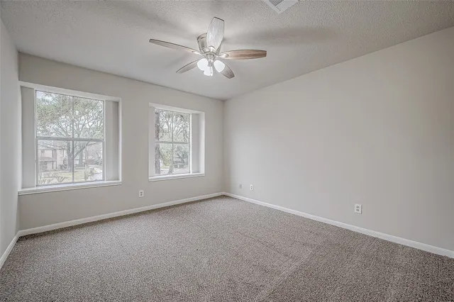 an empty room with chandelier fan and windows