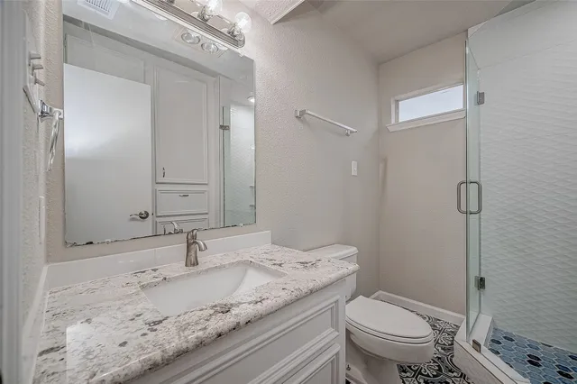 a bathroom with a granite countertop sink toilet and shower