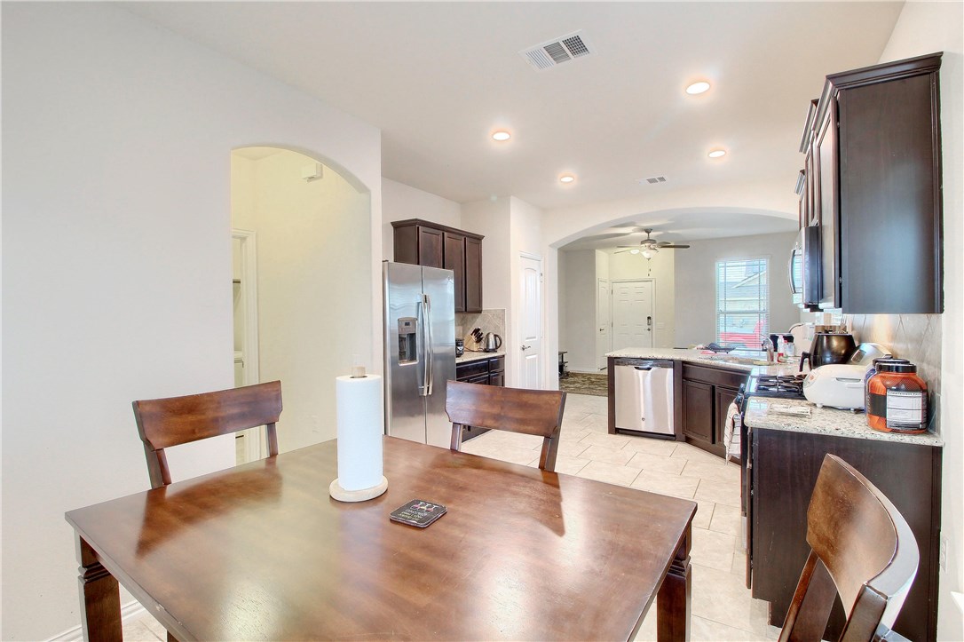 7200 Vail Ridge Street Austin, TX 78744 - Photo 1 of 1 a kitchen with stainless steel appliances granite countertop a refrigerator a stove and white cabinets with wooden floor