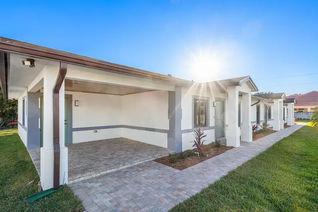 a view of a hallway with stainless steel appliances wooden floor and windows