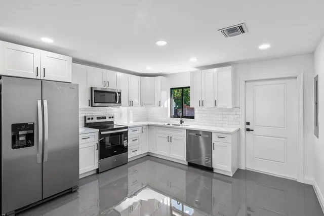 a large white kitchen with a lot of counter space and a refrigerator