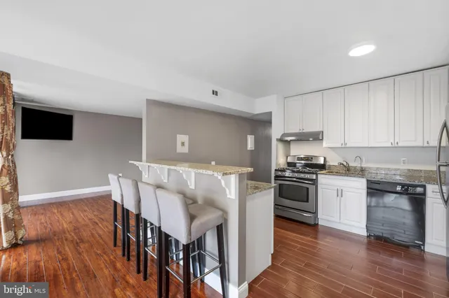 a large kitchen with stainless steel appliances granite countertop a lot of counter space and wooden floor