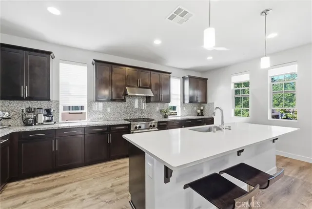 a kitchen with stainless steel appliances a sink a stove a refrigerator cabinets and a window
