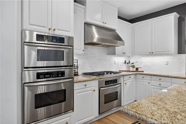 a kitchen with stainless steel appliances granite countertop a stove top oven a sink dishwasher and a fireplace with wooden floor