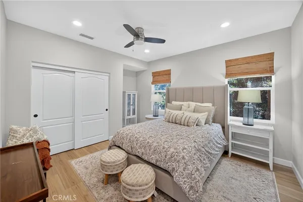 a spacious bedroom with a bed a dresser and wooden floor
