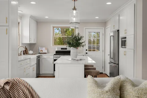 a room with stainless steel appliances kitchen island granite countertop a refrigerator and a sink