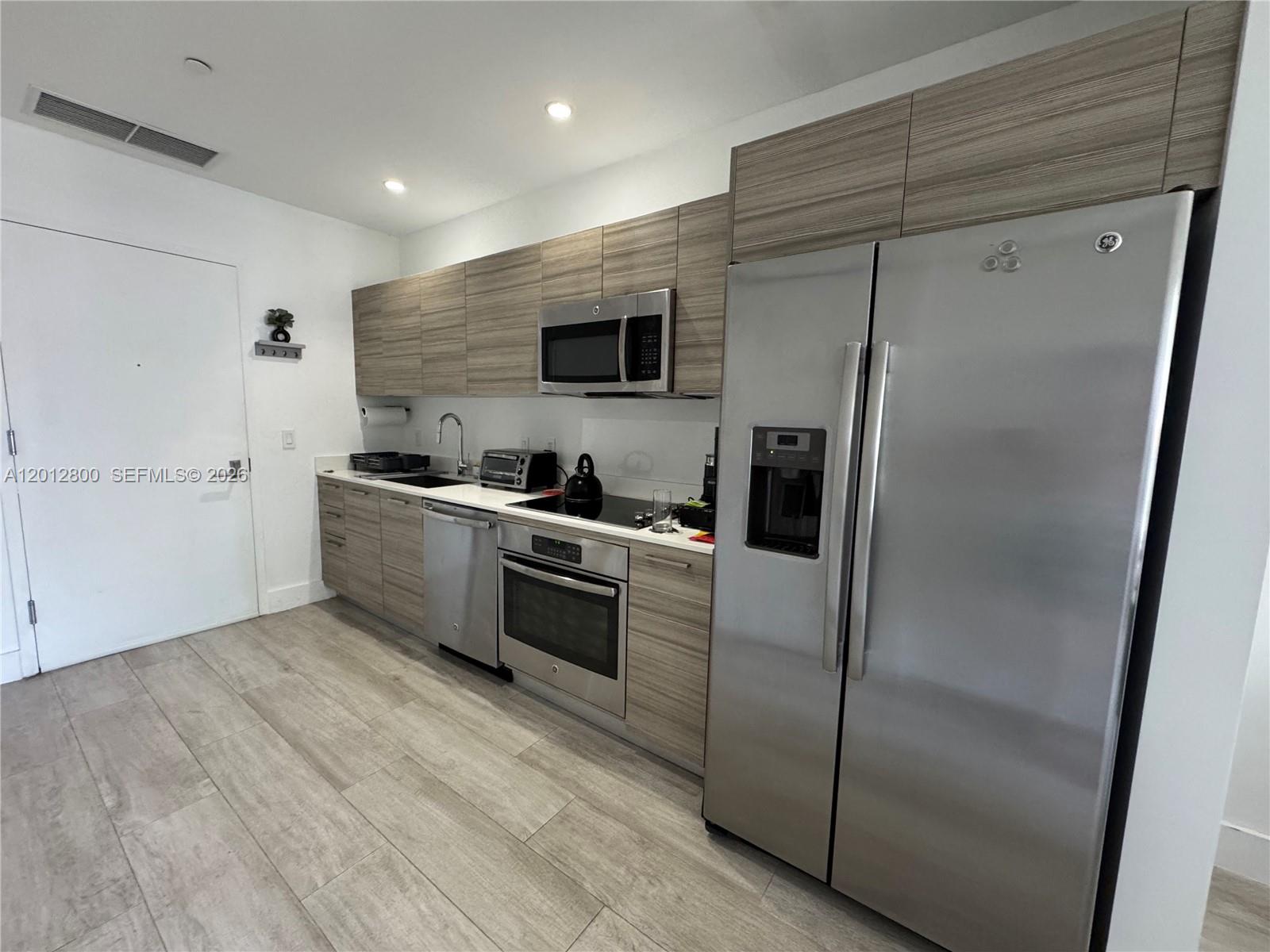 121 Northeast 34th Street, Unit L601 Miami, FL 33137 - Photo 4 of 32 a kitchen with stainless steel appliances granite countertop a refrigerator and a sink