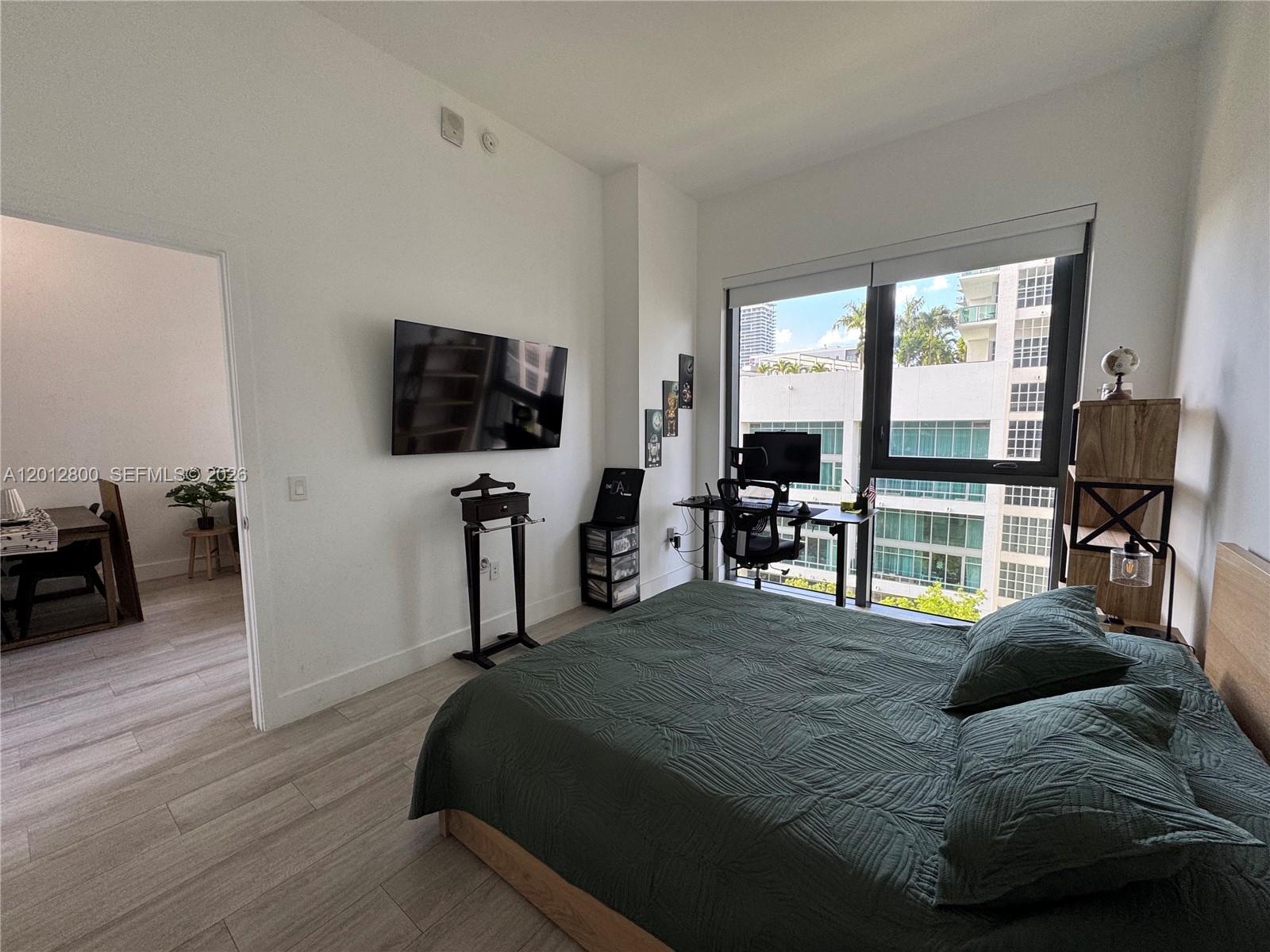 121 Northeast 34th Street, Unit L601 Miami, FL 33137 - Photo 9 of 32 a bedroom with furniture and a flat screen tv