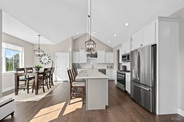 a kitchen with stainless steel appliances a dining table chairs stove and refrigerator