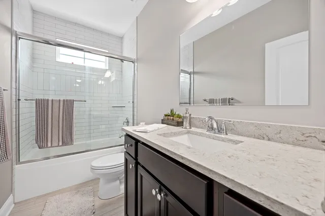 a bathroom with a granite countertop sink a toilet a mirror and shower