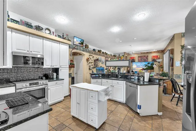 a kitchen with stainless steel appliances kitchen island granite countertop a stove and cabinets