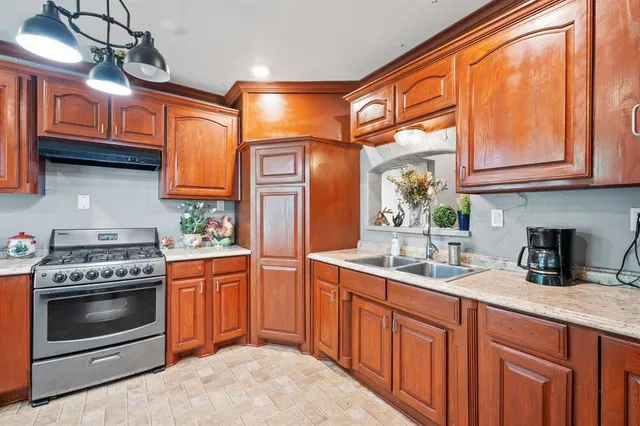 a kitchen with stainless steel appliances granite countertop a stove a sink and dishwasher wooden cabinets with a granite countertops