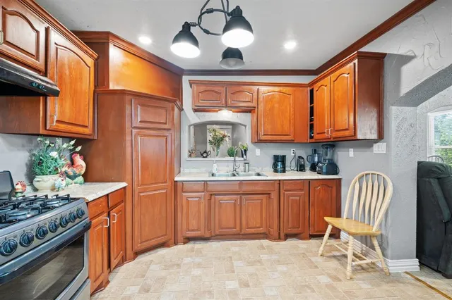 a kitchen with stainless steel appliances granite countertop a stove a sink dishwasher and a refrigerator with wooden floor
