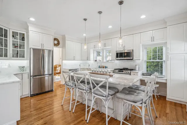 a kitchen with stainless steel appliances granite countertop a refrigerator a stove a sink dishwasher and a dining table with wooden floor