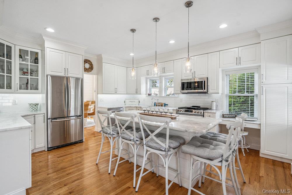 1 Bayview Avenue Islip, NY 11751 - Photo 5 of 18 a kitchen with stainless steel appliances granite countertop a refrigerator a stove a sink dishwasher and a dining table with wooden floor