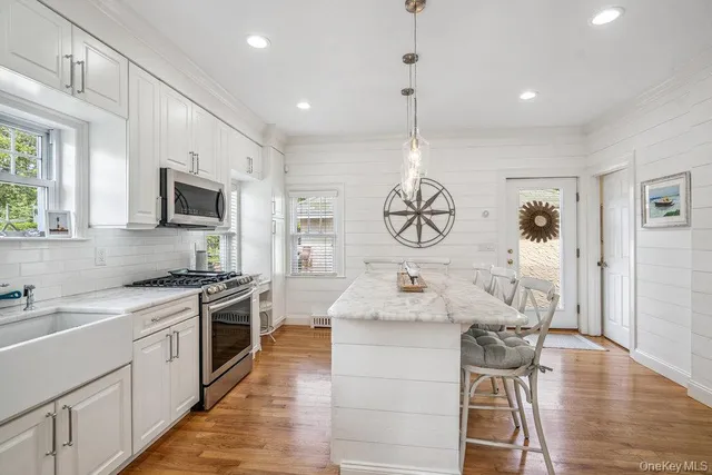 a kitchen with stainless steel appliances granite countertop a stove top oven a sink dishwasher a dining table and chairs with wooden floor