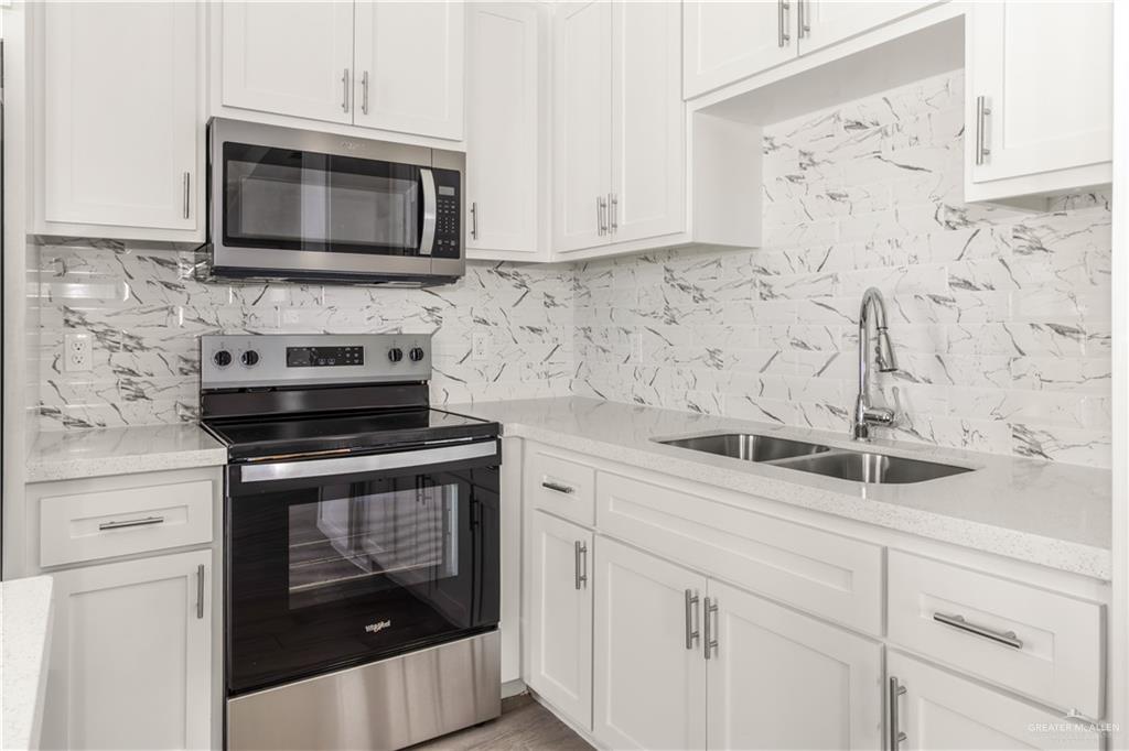 3186 Briggs Road, Unit 1 Weslaco, TX 78596 - Photo 7 of 13 a kitchen with white cabinets stainless steel appliances and sink