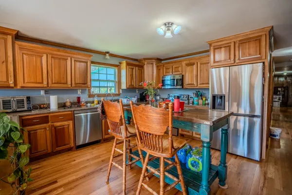 a kitchen with stainless steel appliances granite countertop a refrigerator a stove top oven a sink dishwasher and wooden cabinets with wooden floor