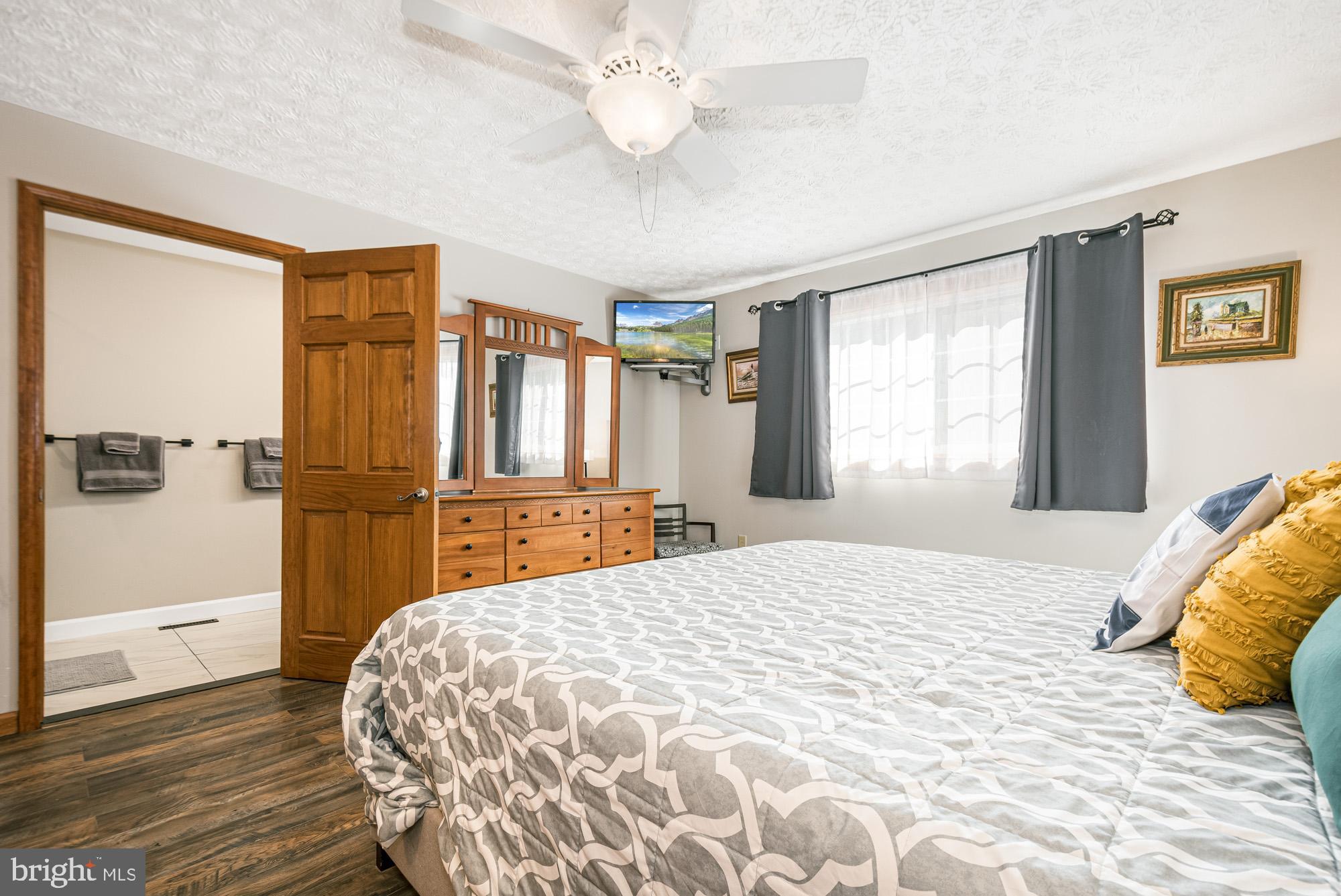 390 Glen Cove Road Swanton, MD 21561 - Photo 29 of 73 a bedroom with a large bed a chandelier and a window