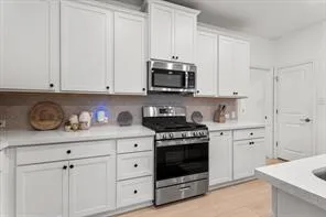 a kitchen with granite countertop white cabinets and stainless steel appliances
