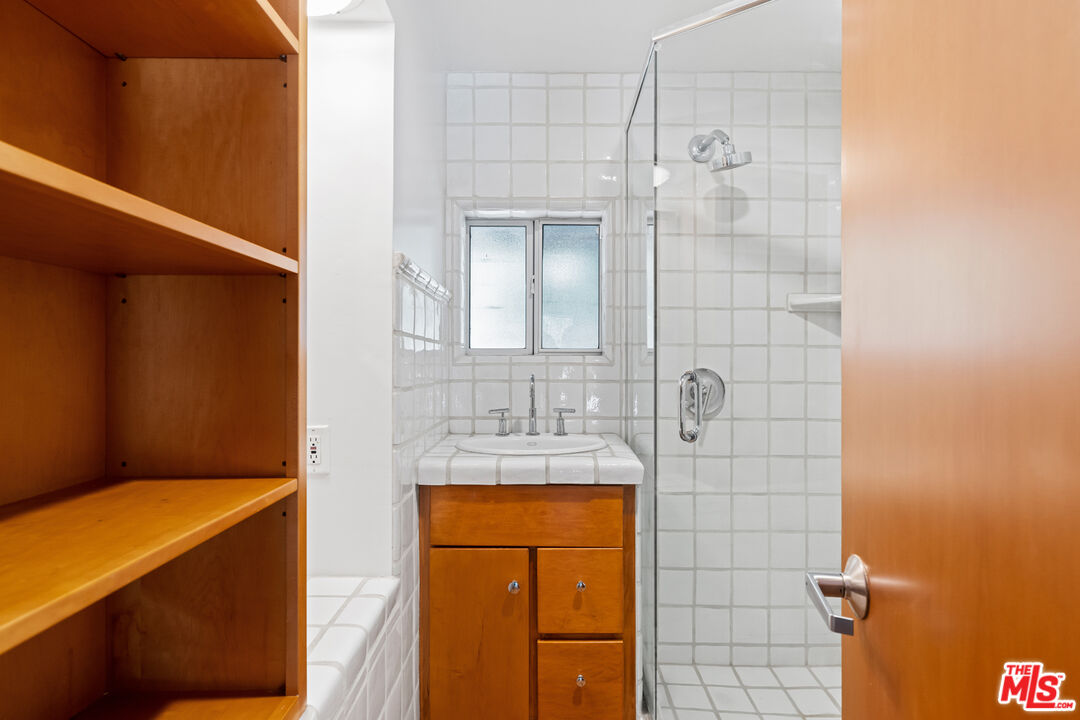 1776 Old Ranch Road Los Angeles, CA 90049 - Photo 16 of 24 a bathroom with a granite countertop sink a mirror and shower