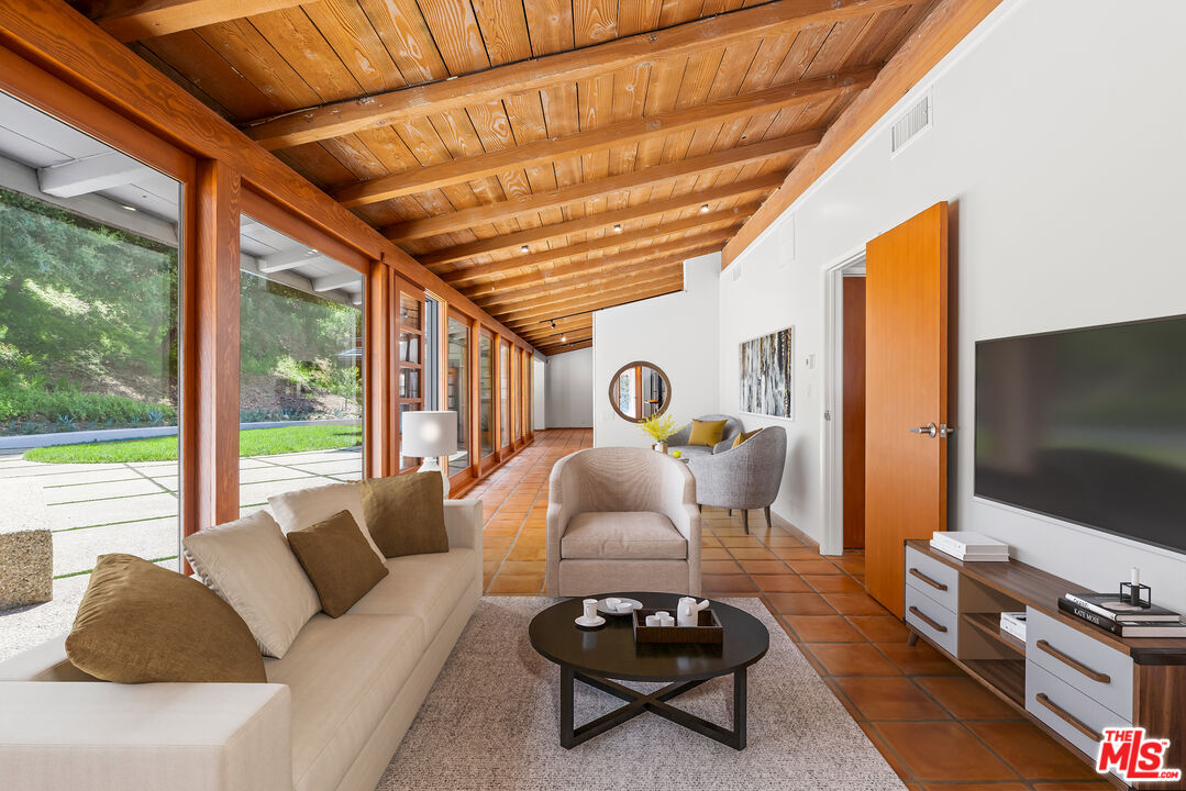 1776 Old Ranch Road Los Angeles, CA 90049 - Photo 5 of 24 a living room with furniture a flat screen tv and a floor to ceiling window