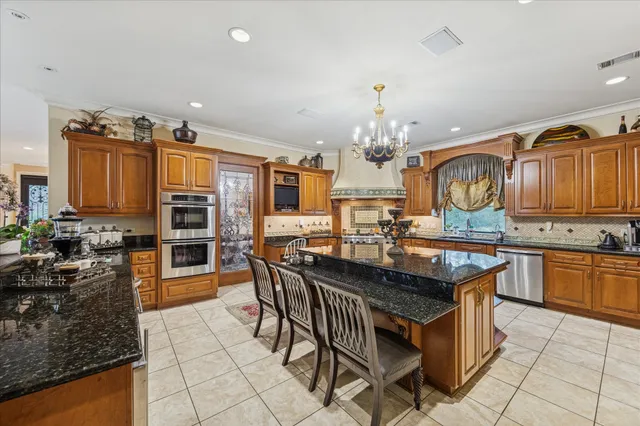 a kitchen with granite countertop a stove a sink a dining table and chairs