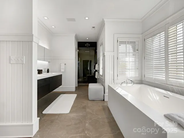 a large en suite bathroom with a tub double vanity and windows