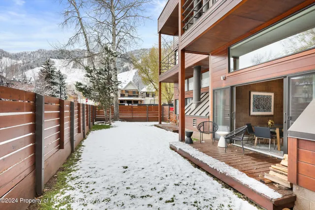 a view of a house with a large tree and wooden fence