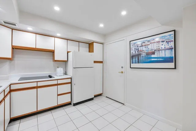 a kitchen with white cabinets a sink and a refrigerator
