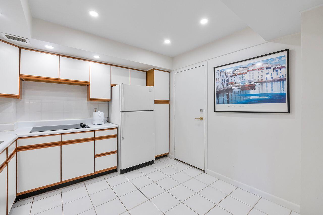 3450 South Ocean Boulevard, Unit 118 Palm Beach, FL 33480 - Photo 10 of 39 a kitchen with white cabinets a sink and a refrigerator