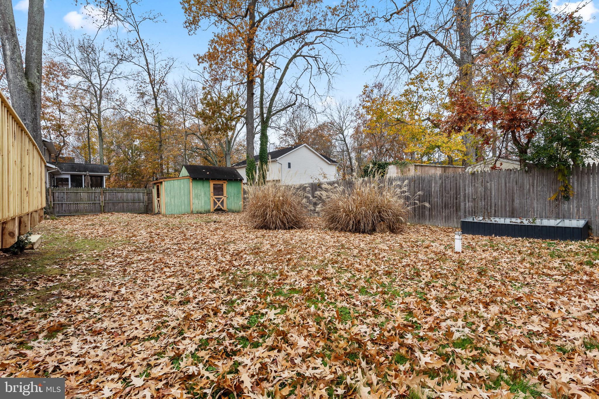 4912 Beech Street Shady Side, MD 20764 - Photo 20 of 42 a backyard of a house with large trees and covered with wooden fence