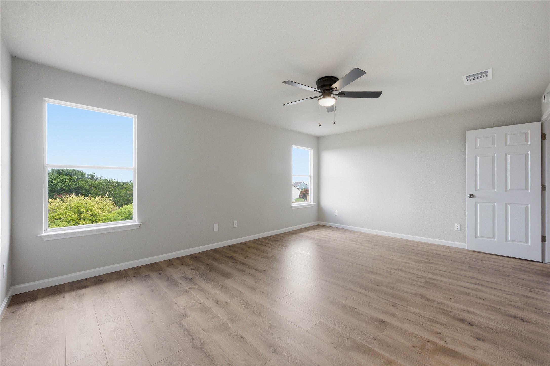 6917 Panda Royle Drive Del Valle, TX 78617 - Photo 13 of 23 A spacious bedroom features light wood flooring and abundant natural illumination from multiple windows.