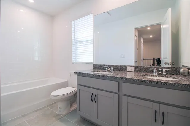 a bathroom with a granite countertop sink a toilet and bathtub