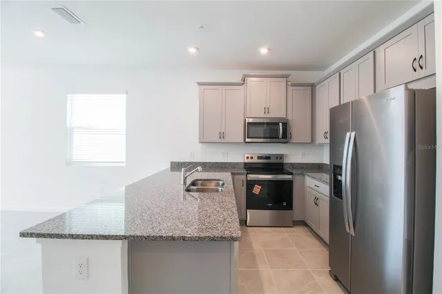 a kitchen with stainless steel appliances granite countertop a refrigerator and a stove