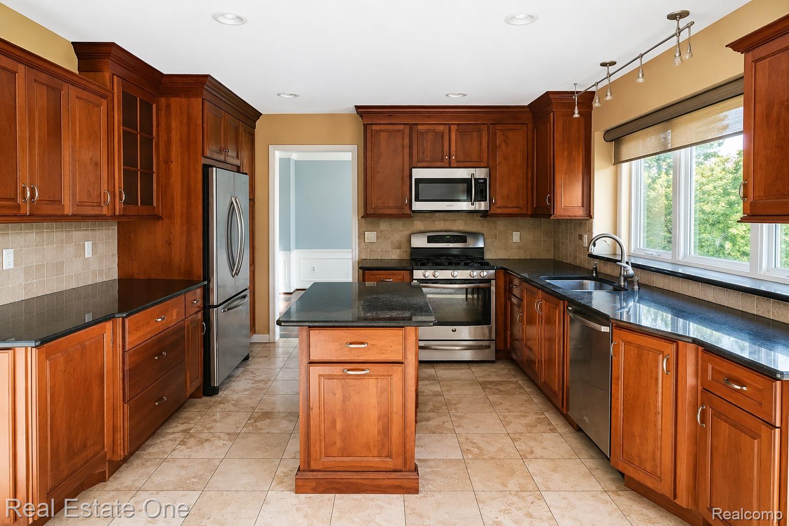 1141 Sandy Ridge Drive Rochester, MI 48306 - Photo 5 of 9 Kitchen featuring wood cabinetry, dark countertops, tiled backsplash, stainless steel appliances, and a central island