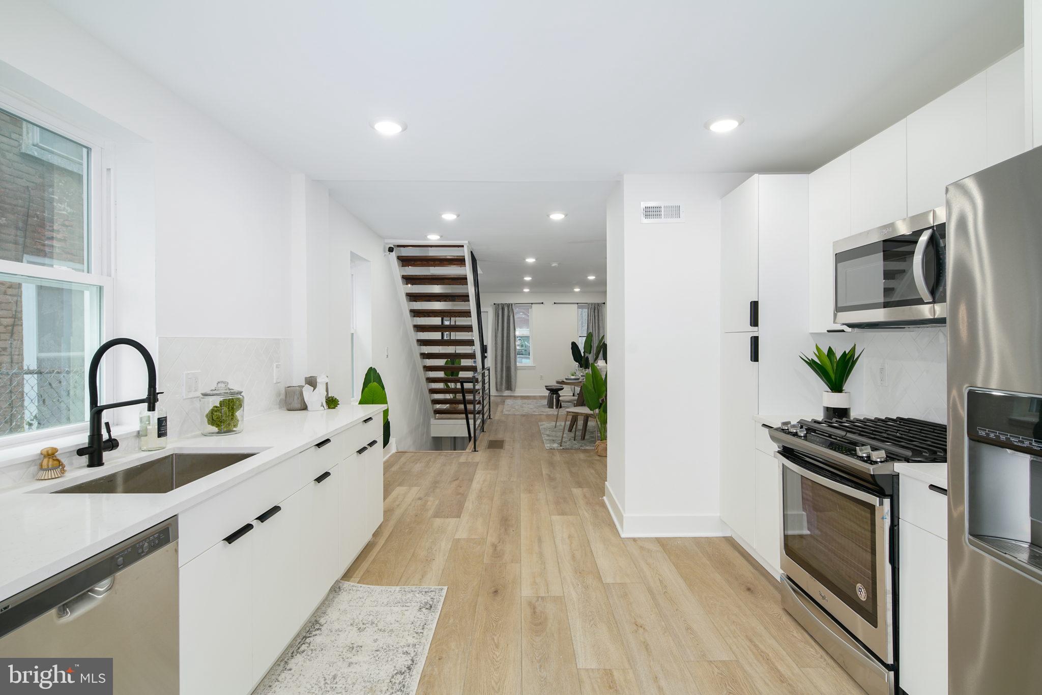 a kitchen with stainless steel appliances a stove refrigerator and a wooden floor