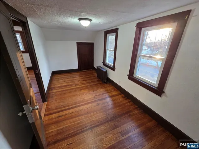 a view of an empty room with wooden floor and windows
