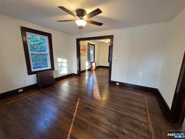 a view of an empty room with a window and wooden floor