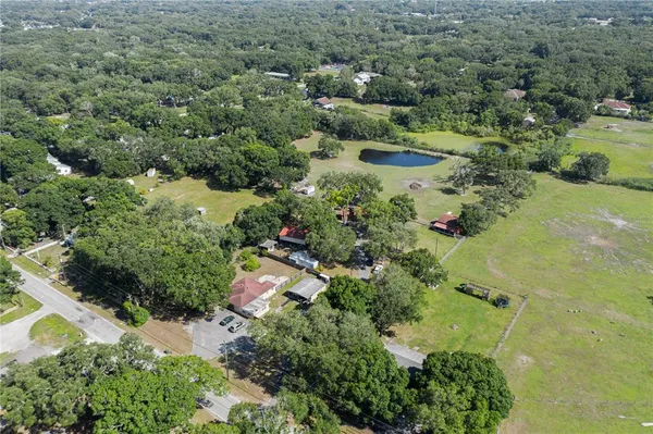 an aerial view of residential house with outdoor space and trees all around